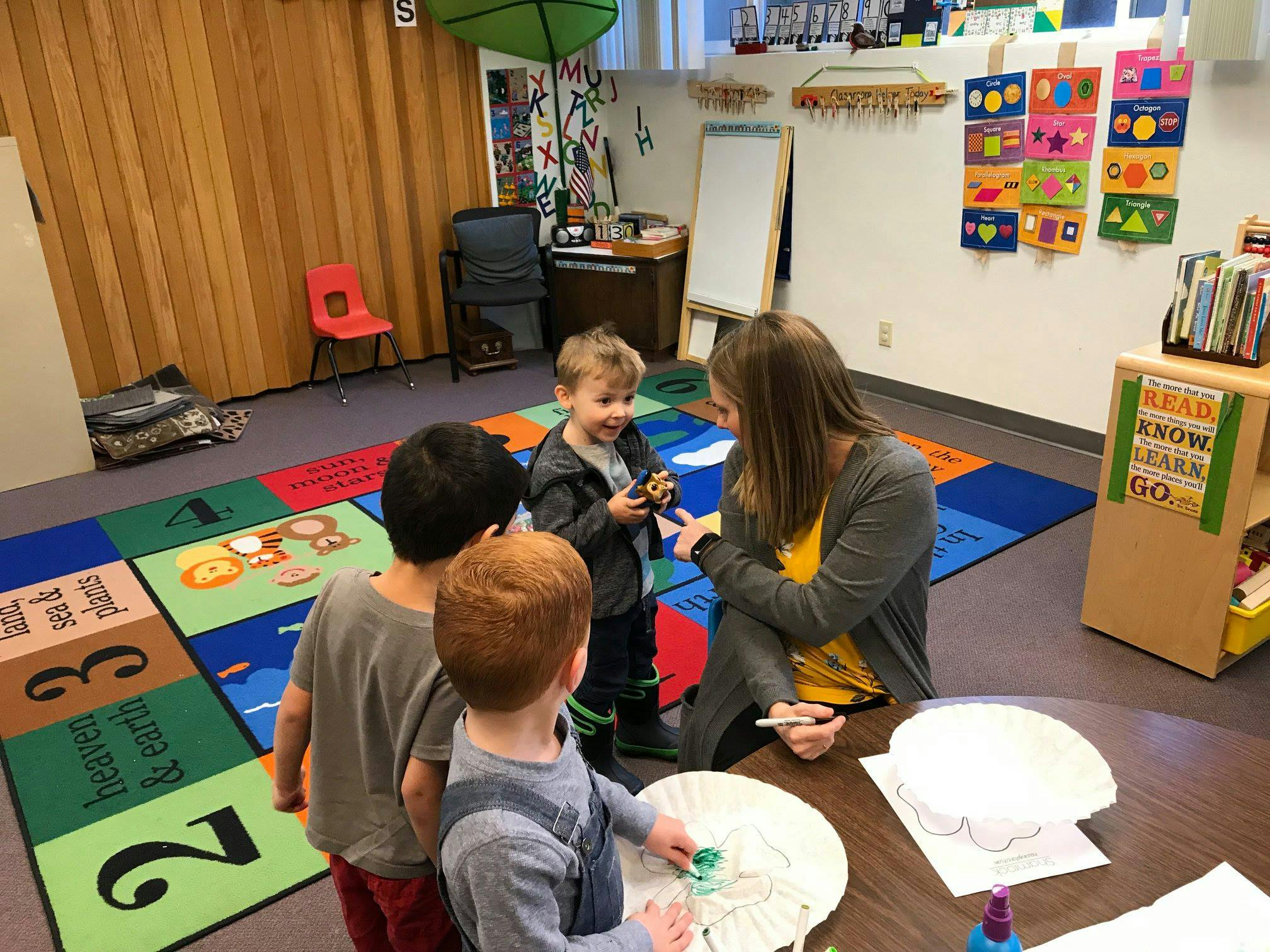 Adult and three children interacting in a classroom