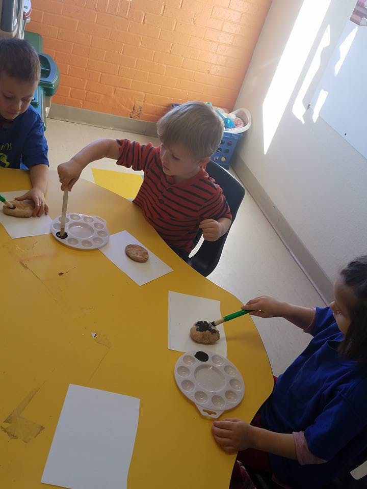 Children painting cookies at a table