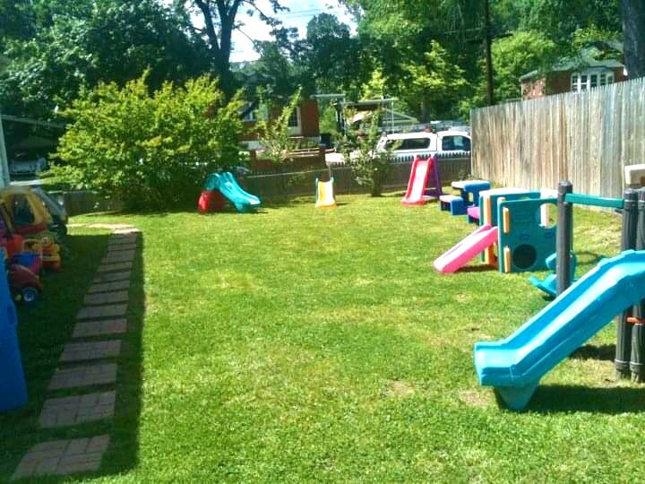 Backyard playground with multiple slides and play structures on grass