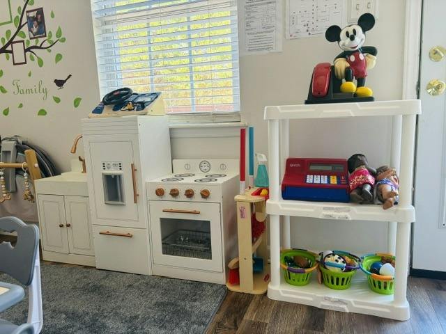 Play area with a toy kitchen and shelves containing toys