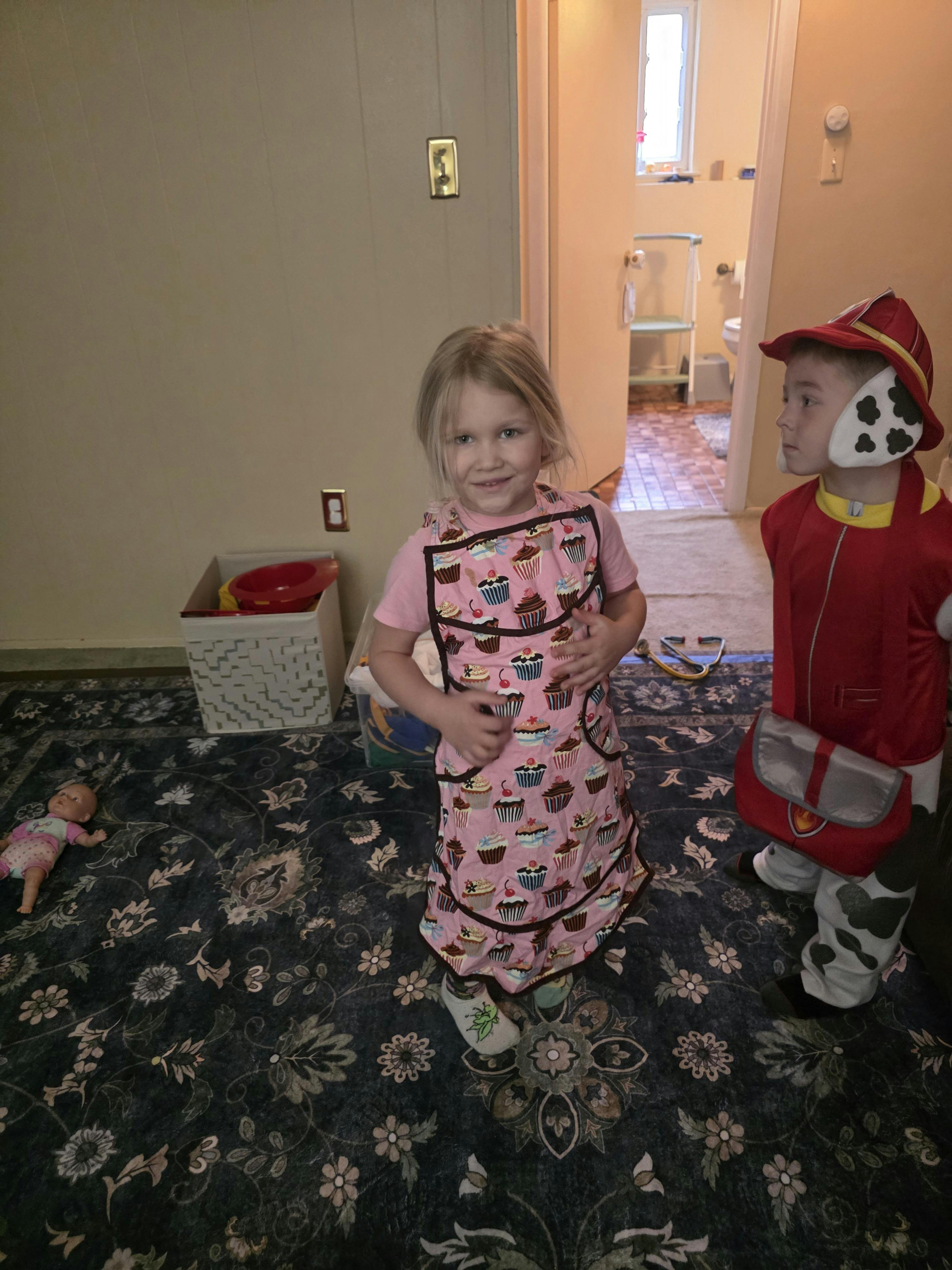 Child wearing a cupcake apron and child in a character costume