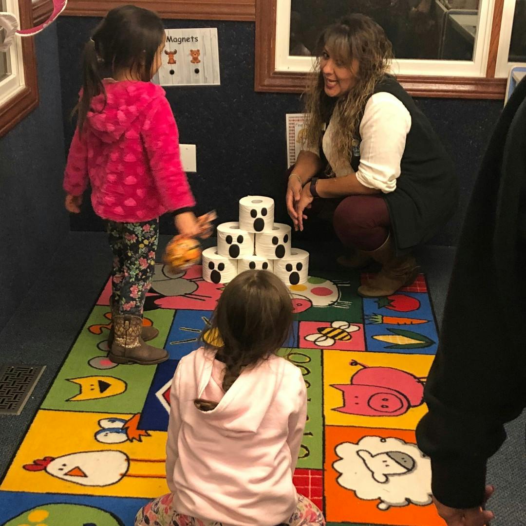 Adult and two children playing with stacked toilet paper rolls