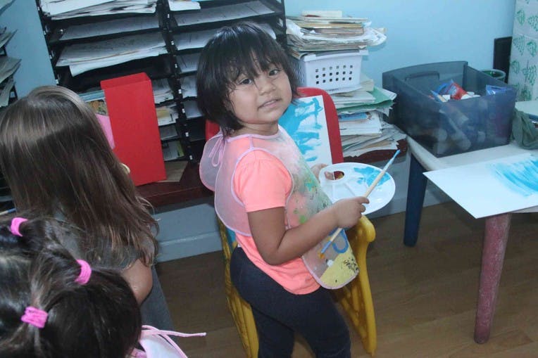 Child holding a paint palette and brush