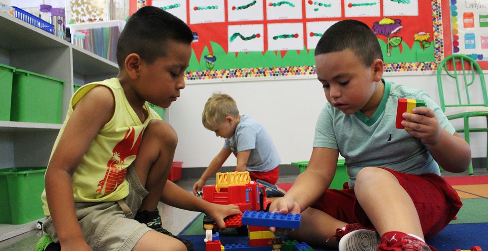 Two children playing with building blocks on the floor