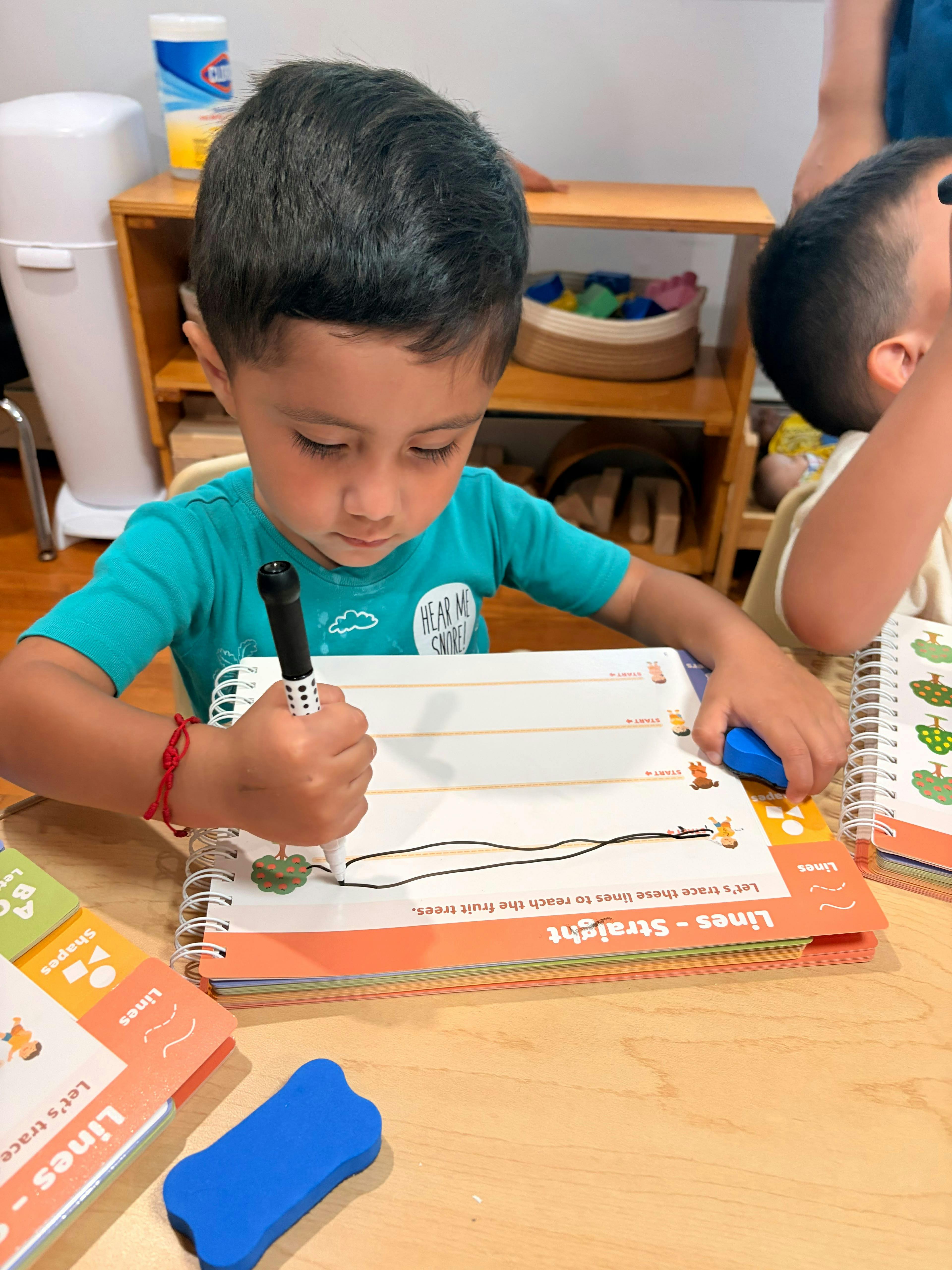 Child tracing lines in a workbook at a table