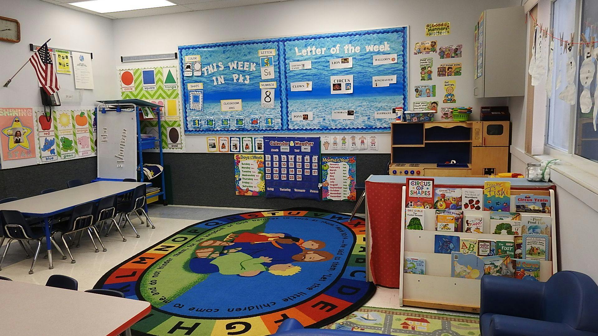 Empty classroom with tables, chairs, and a colorful rug