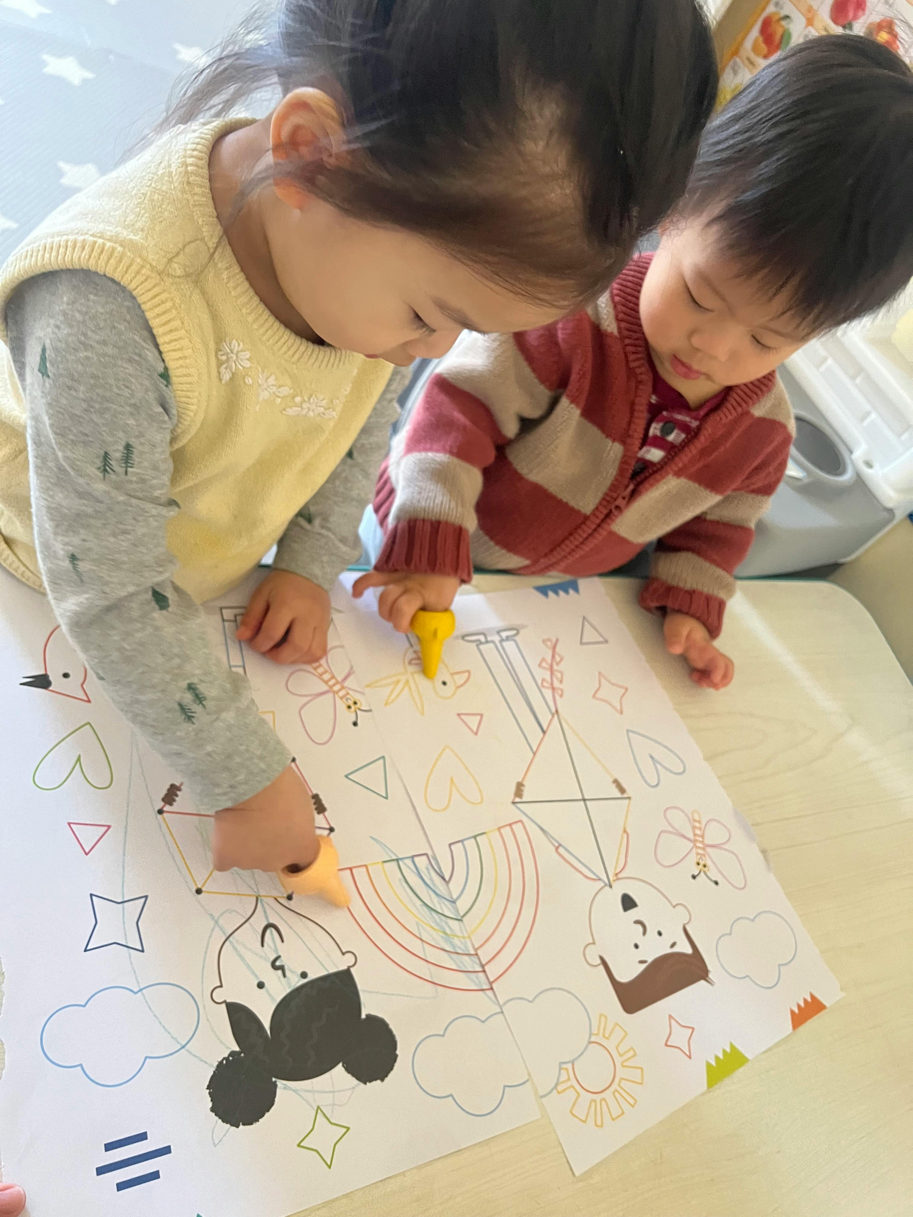 Two children coloring a picture with crayons