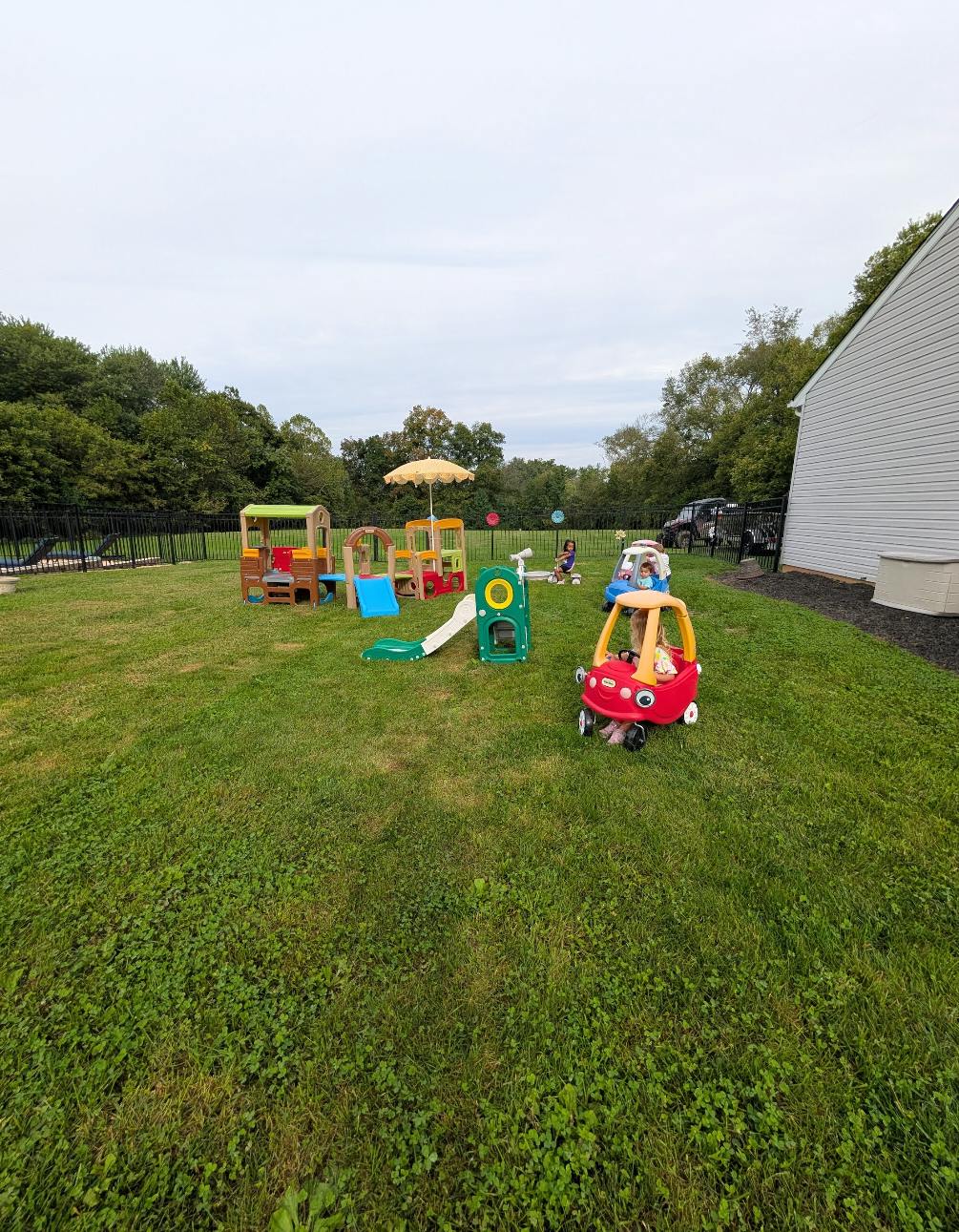Outdoor play area with various toys and play structures on grass