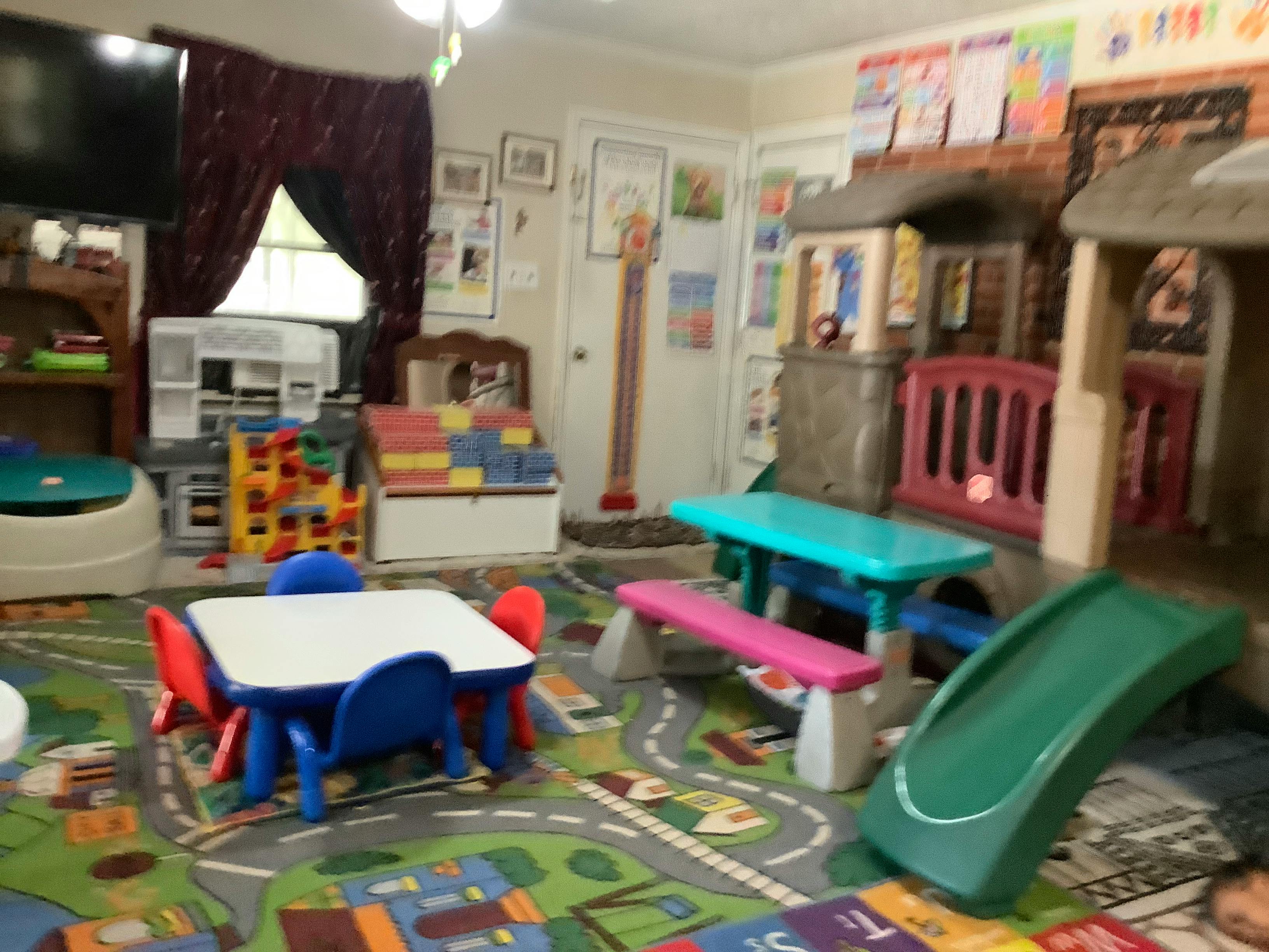 Playroom with small tables, chairs, playhouses, and a slide