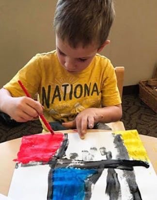 Child painting with a brush on paper