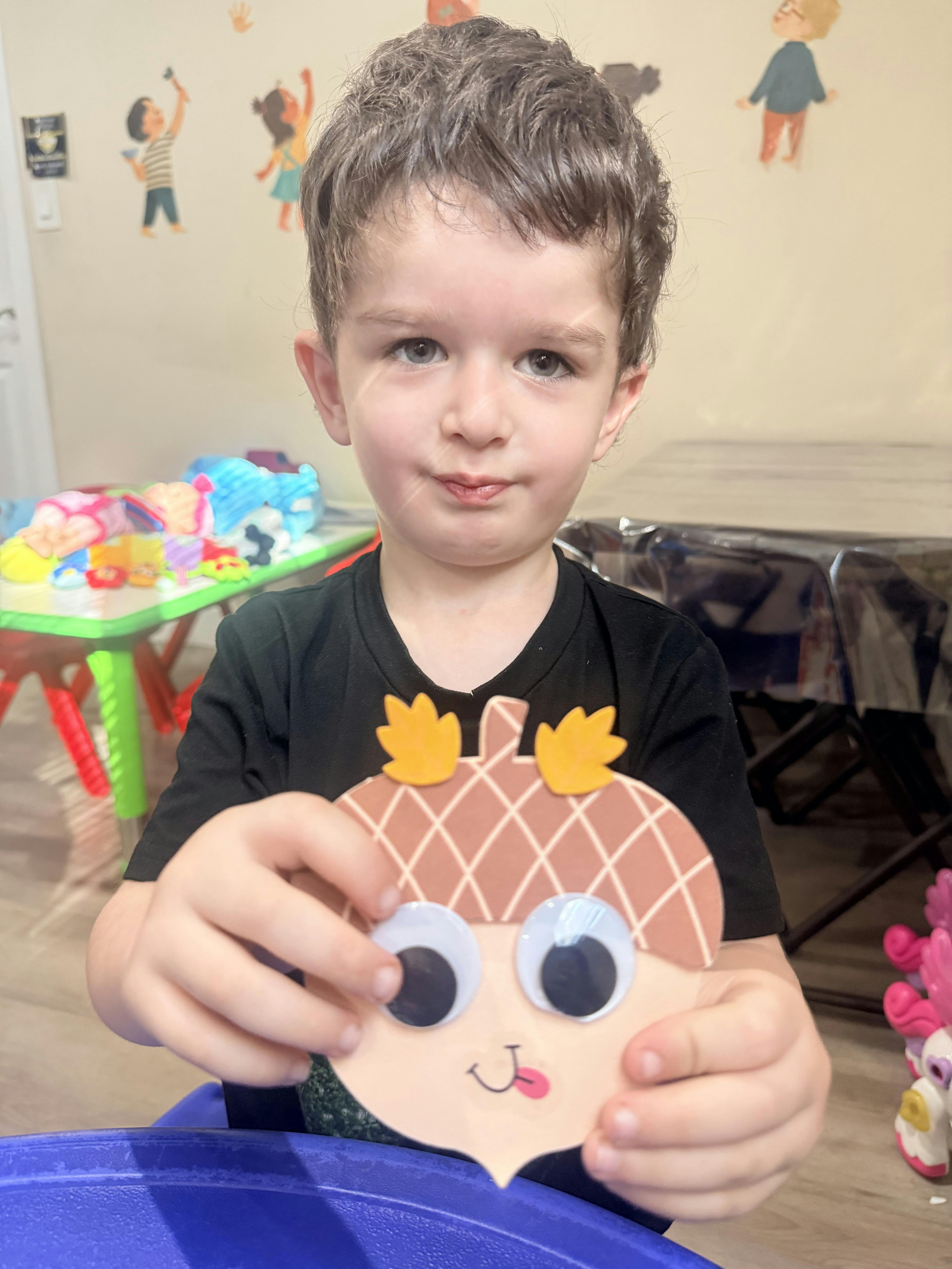 Child holding an acorn-shaped craft with googly eyes