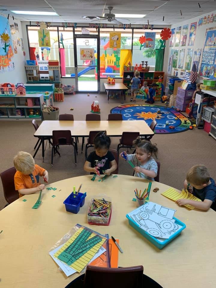 Children sitting at a table doing crafts in a classroom