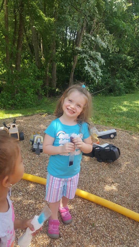 Child holding a purple ice pop on a playground