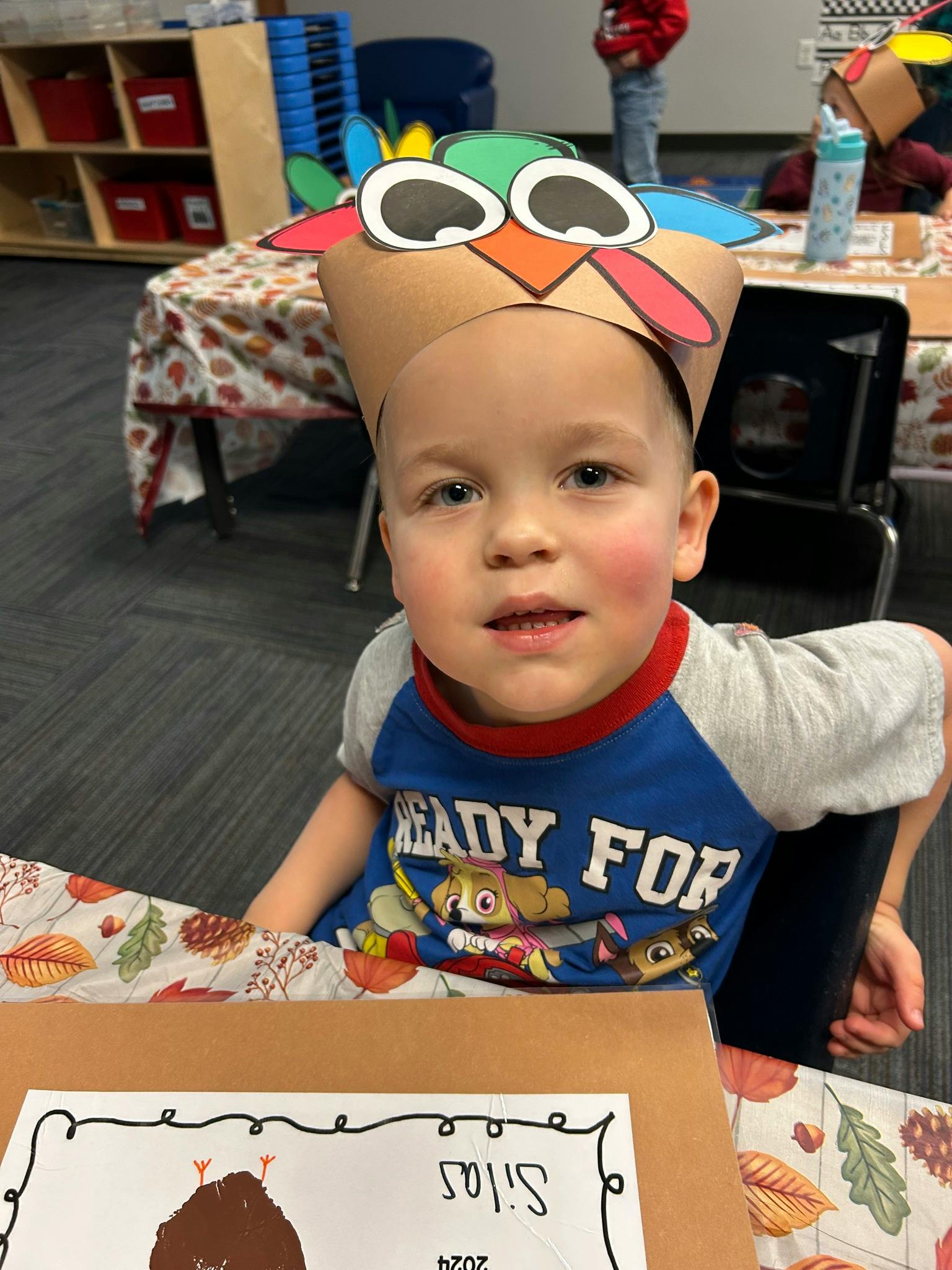 Child wearing a turkey hat in a classroom