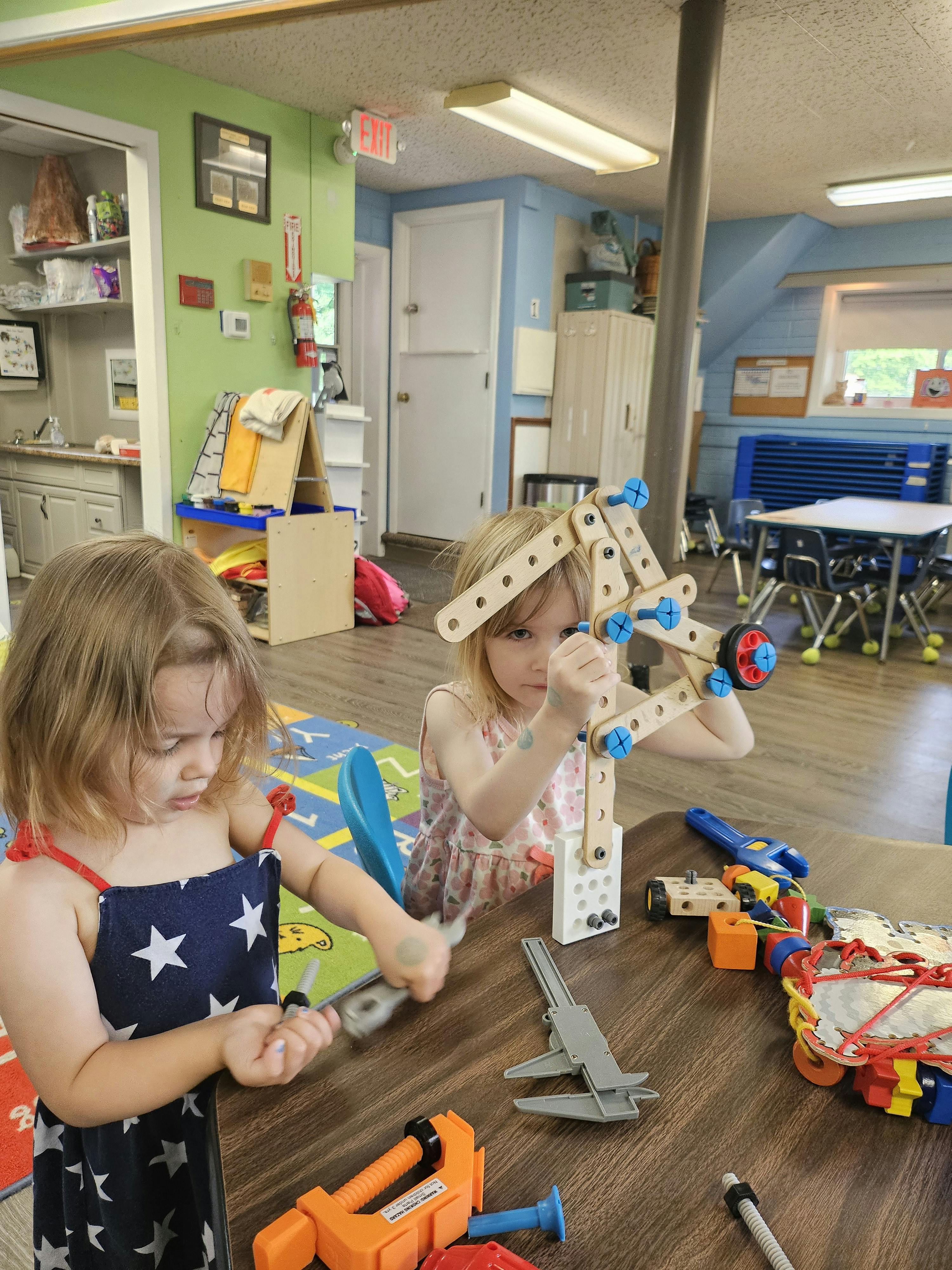 Two children playing with building toys at a table in a classroom