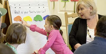 Child pointing at a chart with a person observing