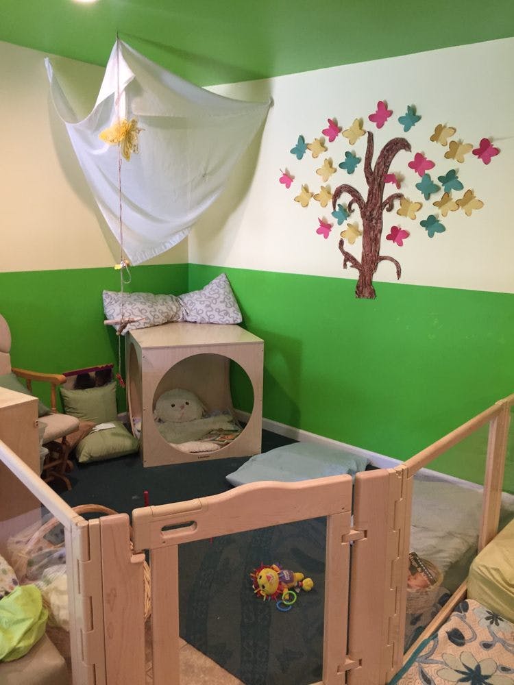 Playroom with a wooden playpen, a tree mural, and a fabric canopy