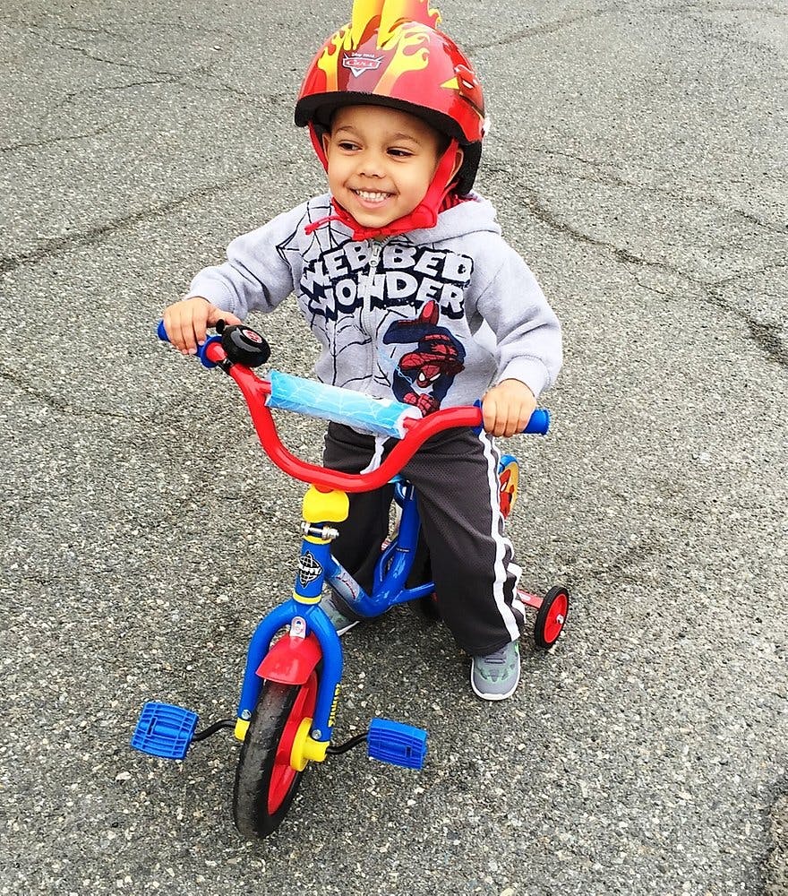 Child wearing a helmet and riding a tricycle