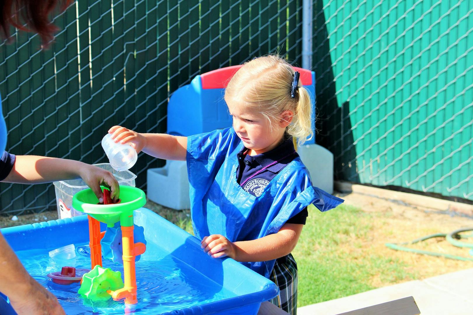 Child pouring water into a water table toy