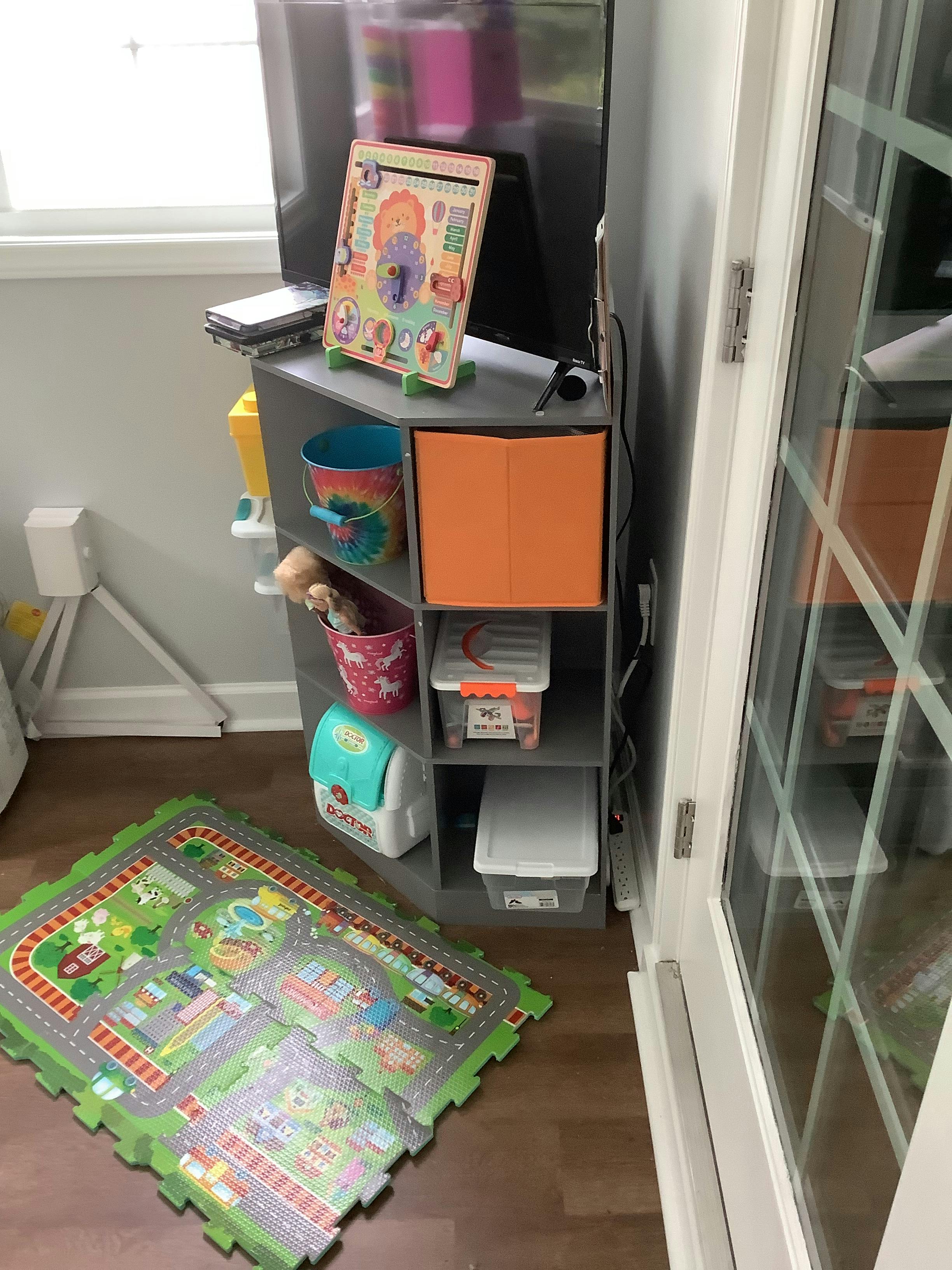 Playmat on floor next to storage shelves with toys