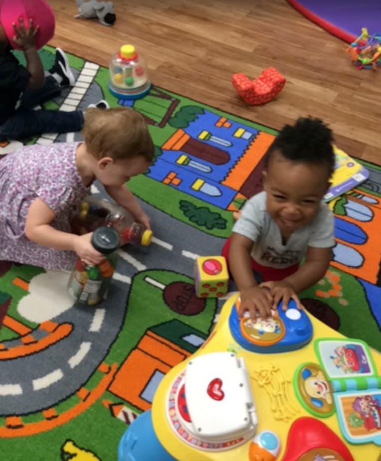 Two children playing with toys on a colorful rug