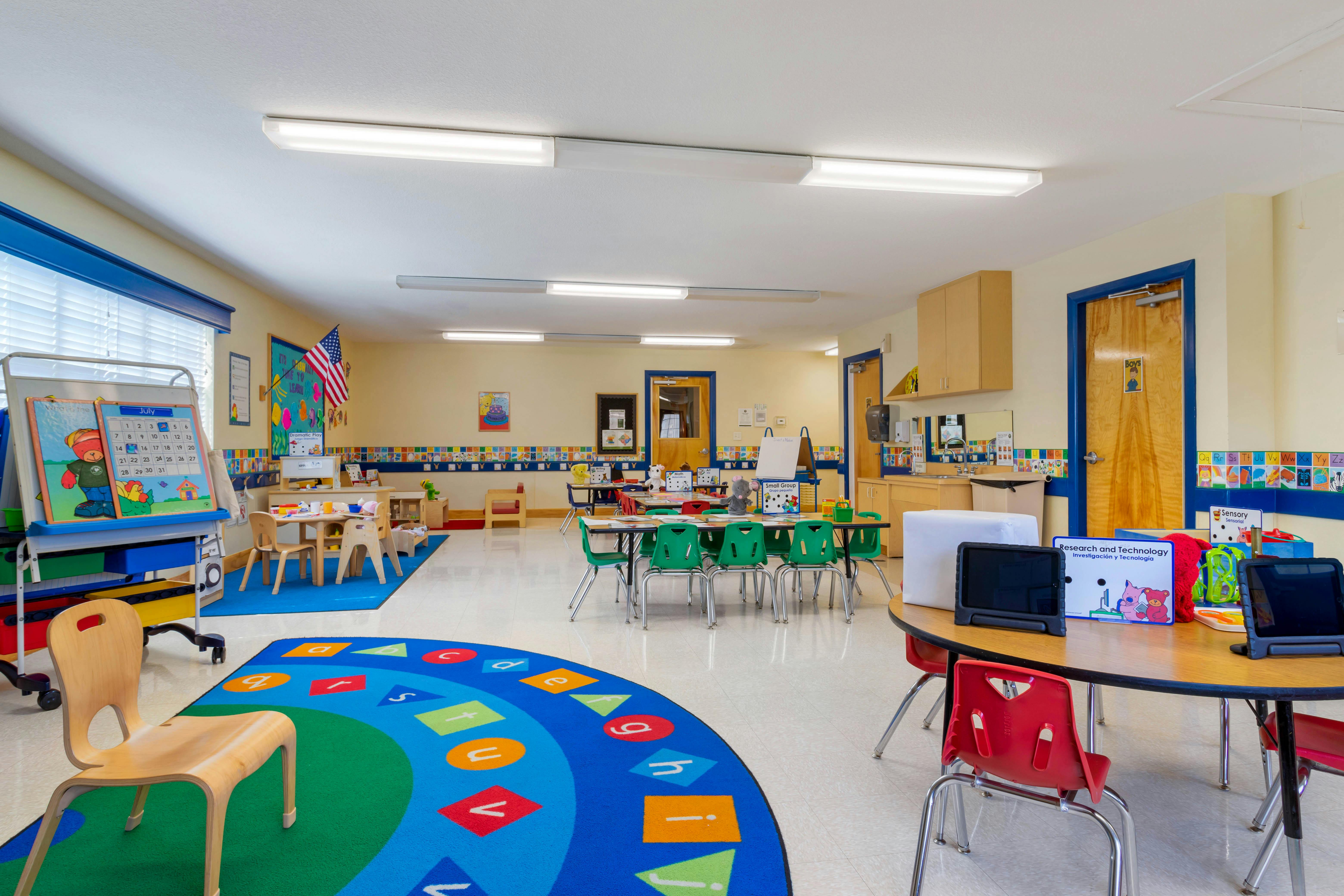 Colorful preschool classroom with various activity stations and furniture