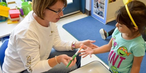 Person holding a brush to a child's hand