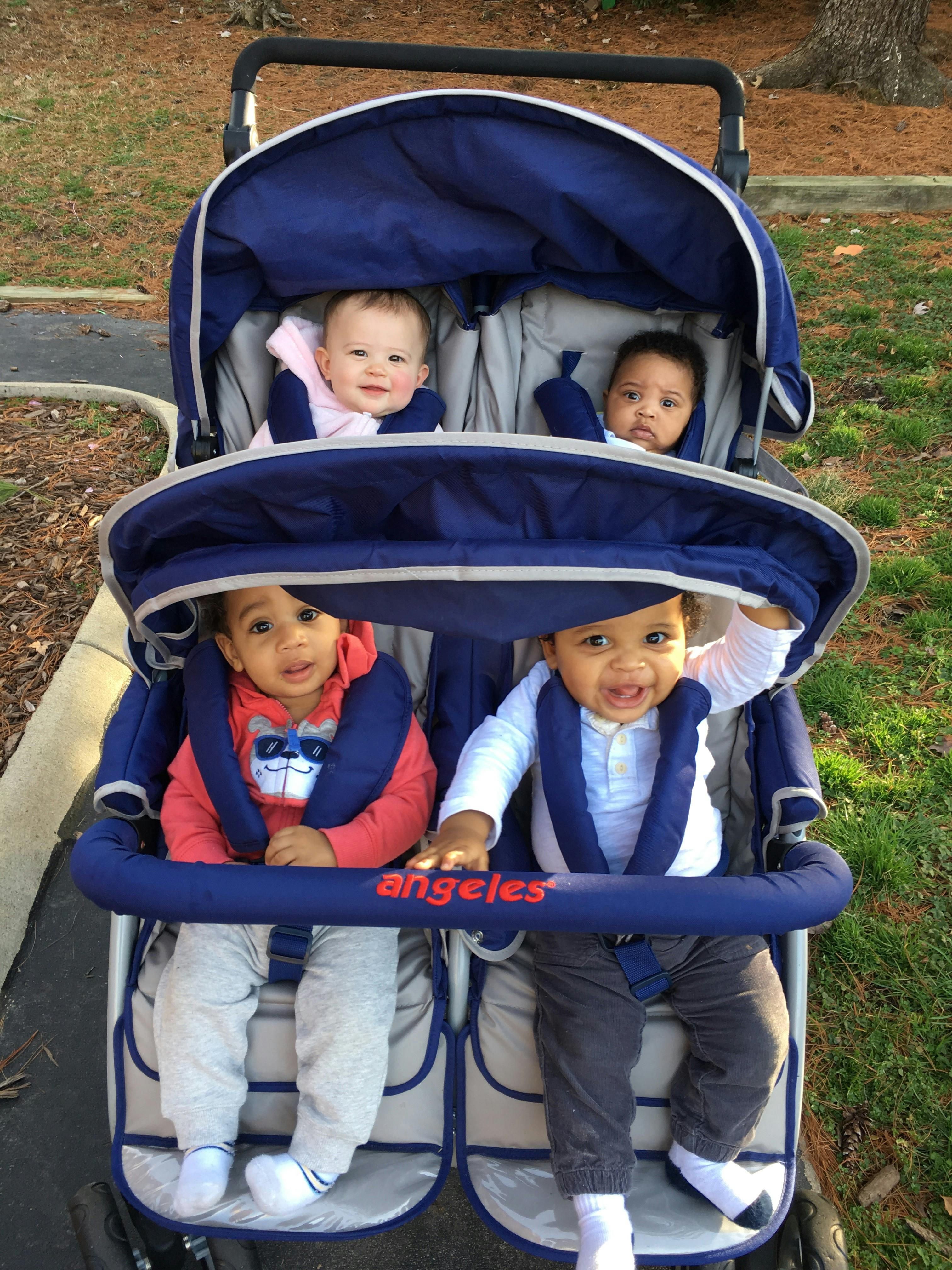 Four babies in a blue double stroller