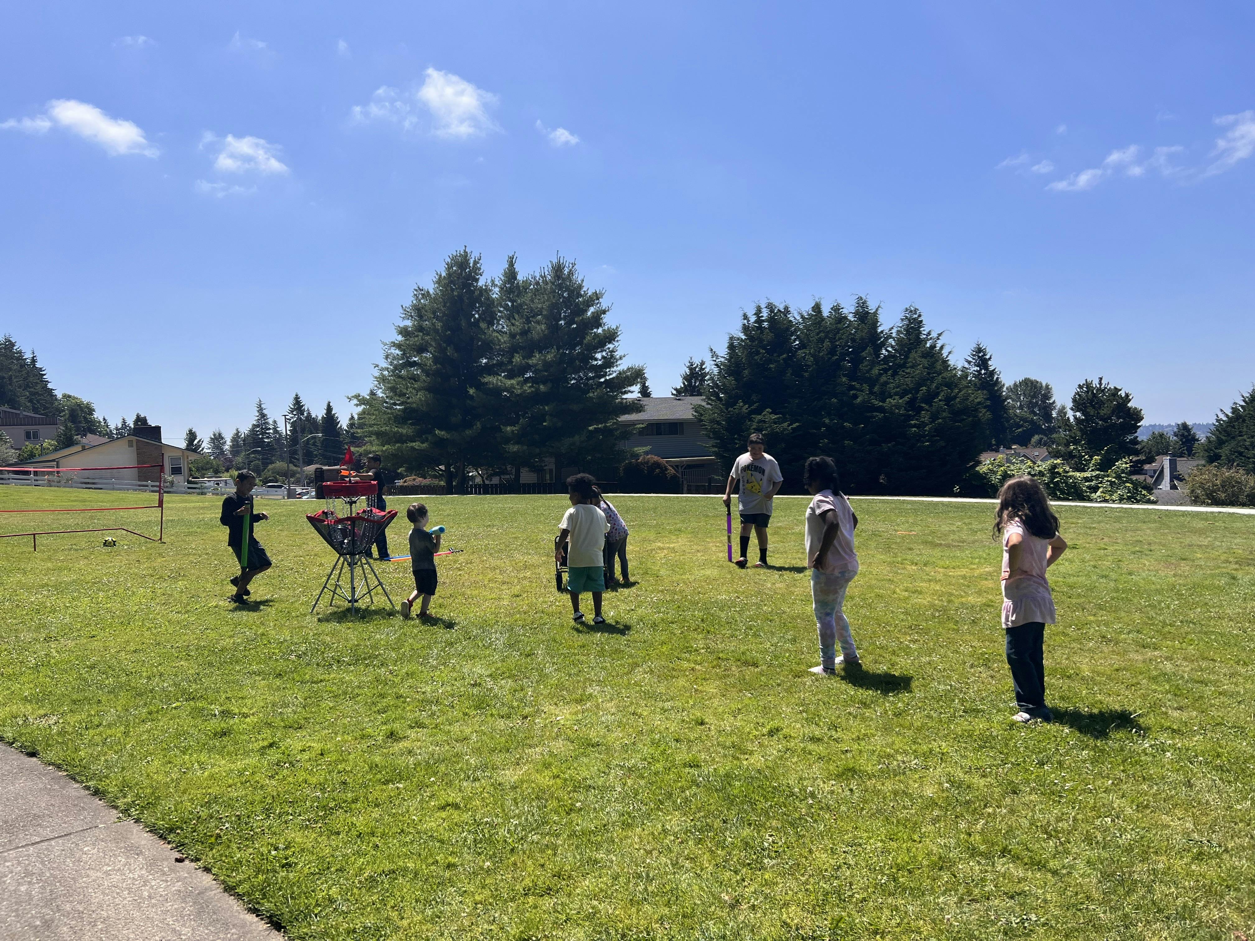 People and children playing outdoors in a grassy field