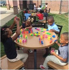 Children playing with colorful building blocks at a table outdoors