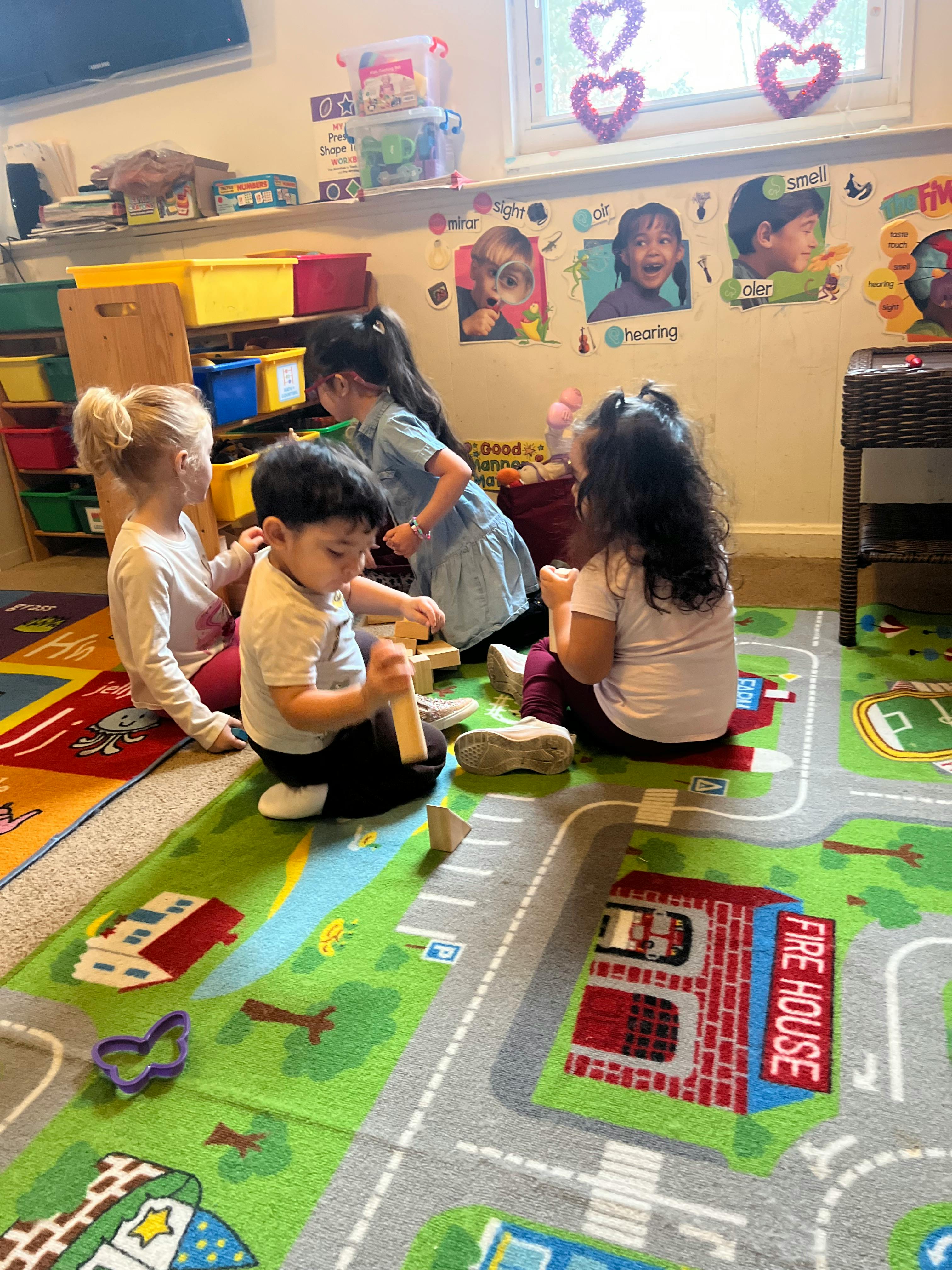 Children playing with wooden blocks on a rug with road map rug
