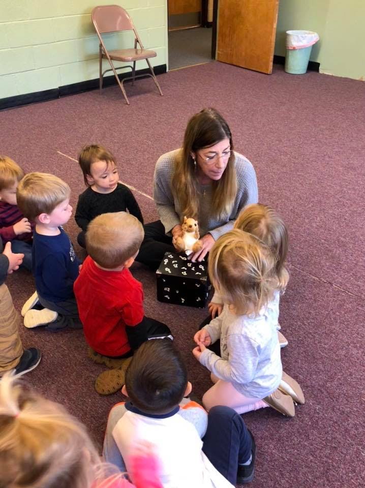 Adult person sitting on floor with children in a circle