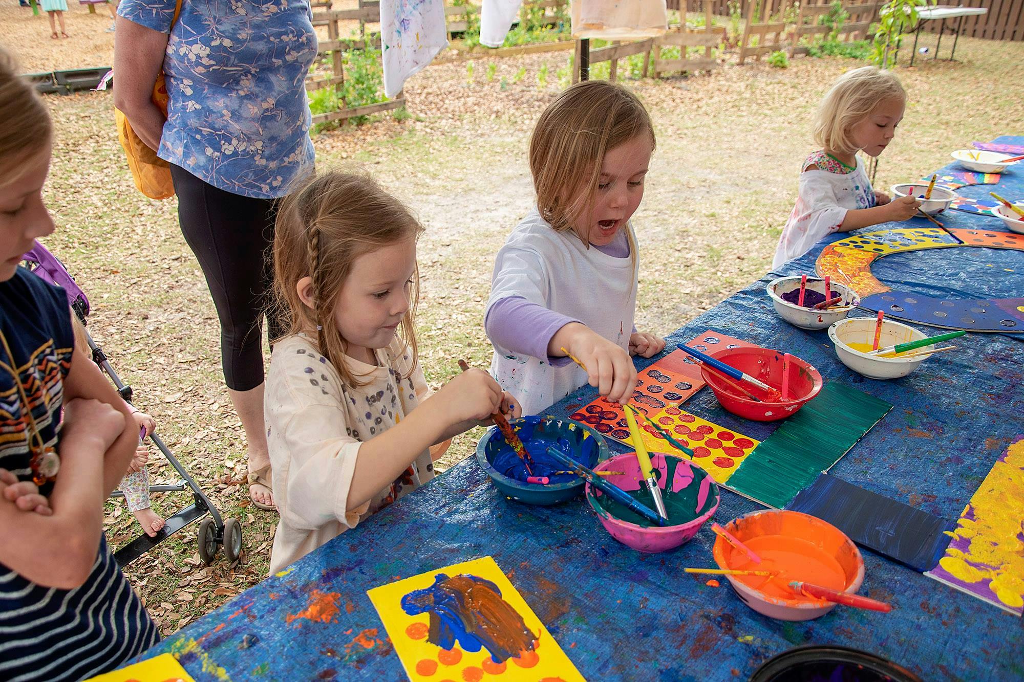 Children painting at a table outdoors