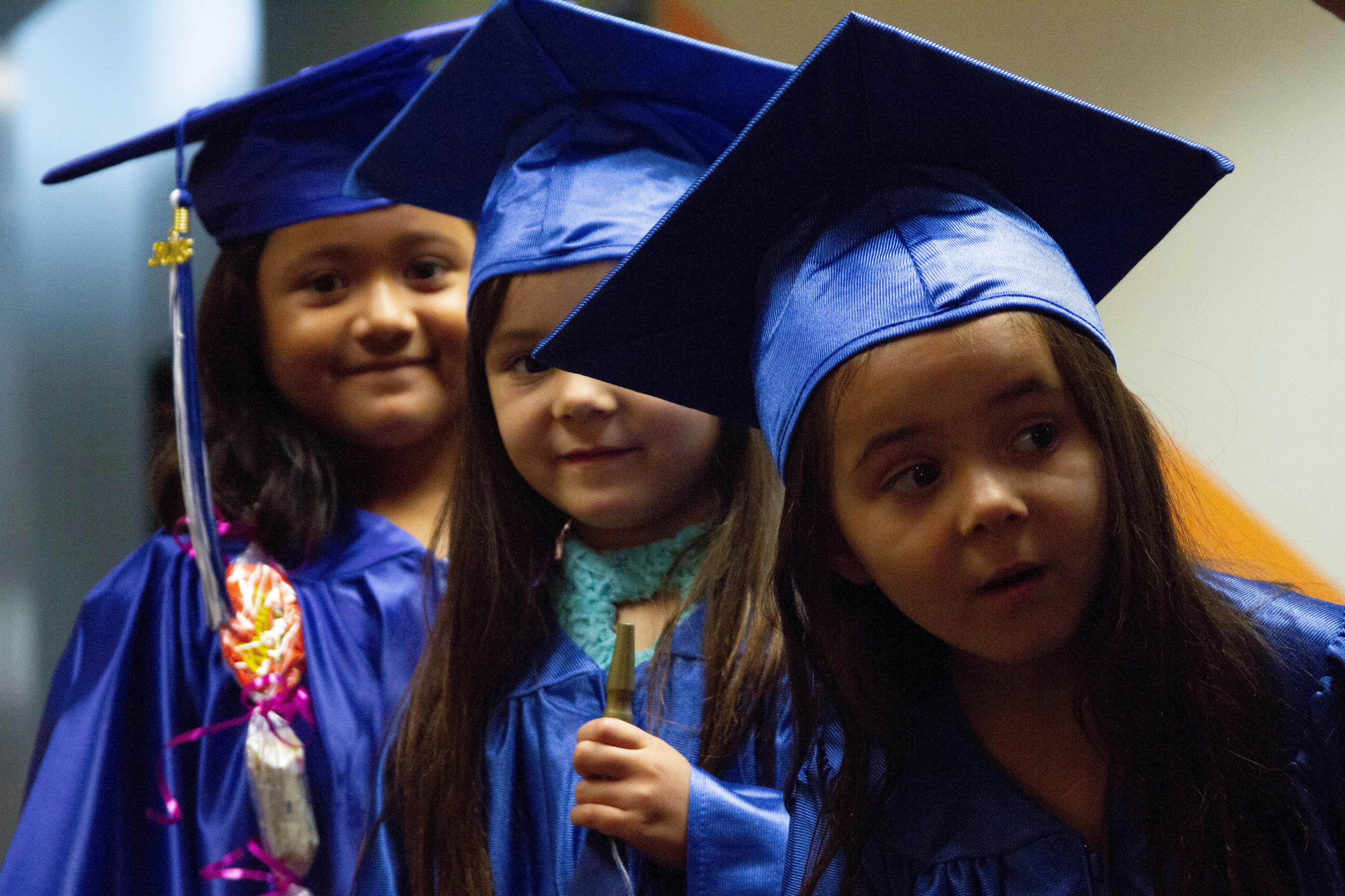 Three children in blue graduation caps and gowns