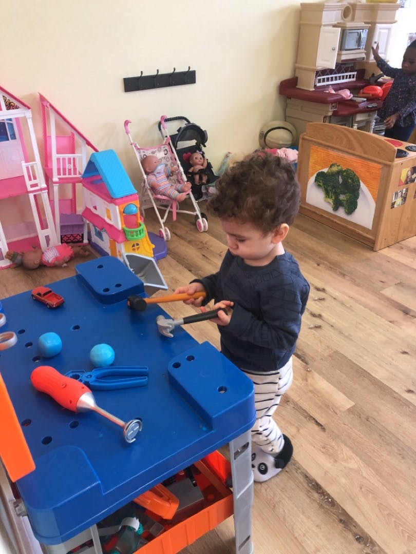 Child playing with toy tools at a blue workbench