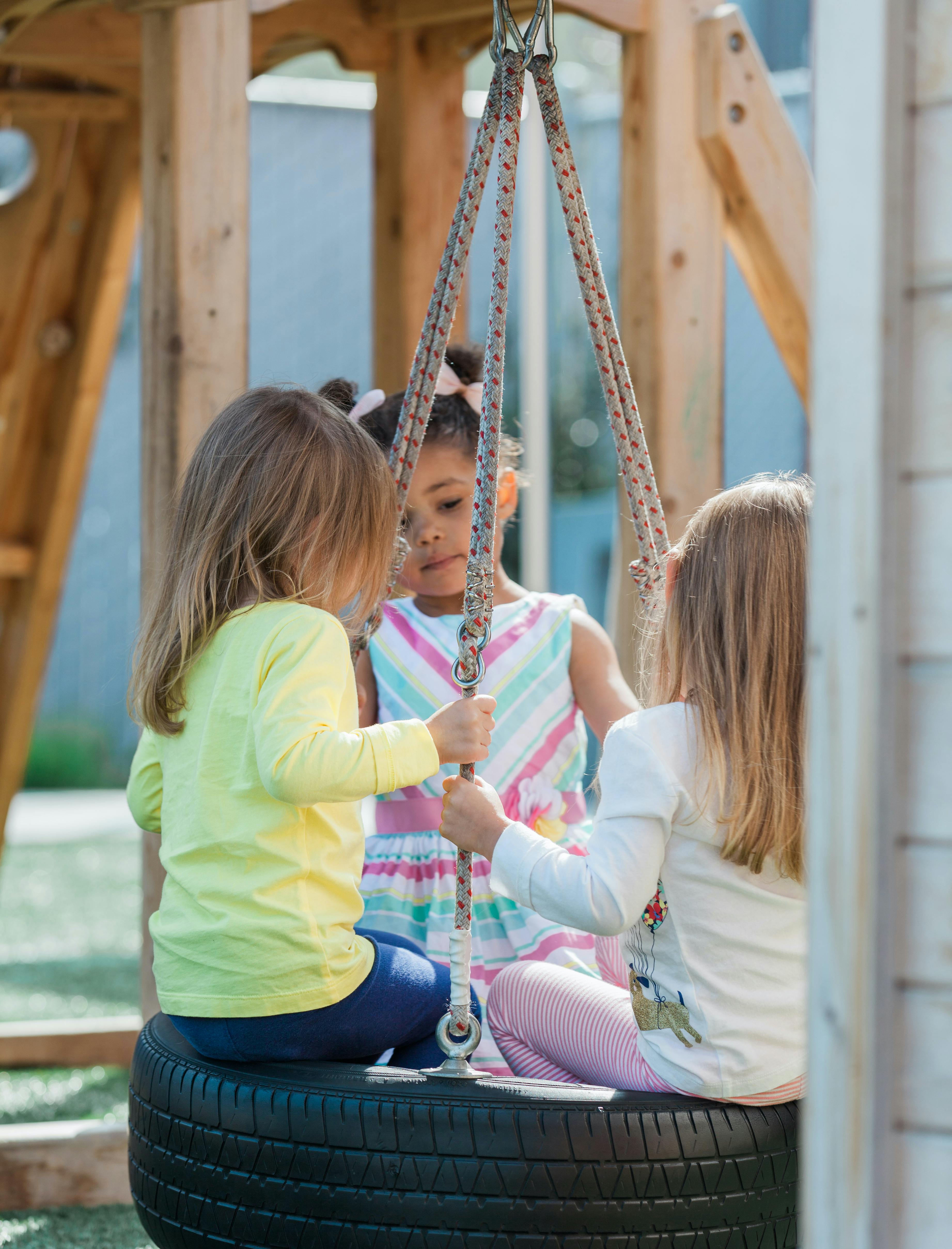 Three children playing on a tire swing