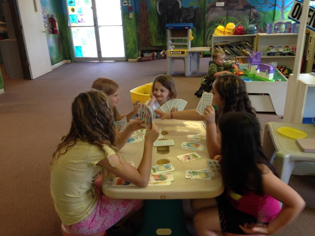 Children playing cards at a table in a classroom