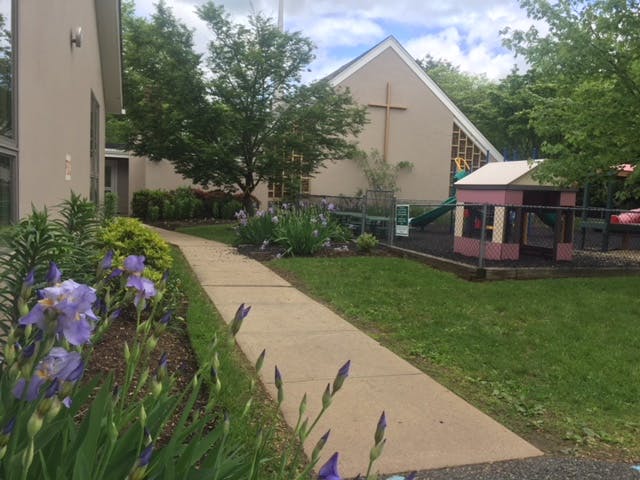 Walkway leading to a building with a cross on its facade, next to a playground