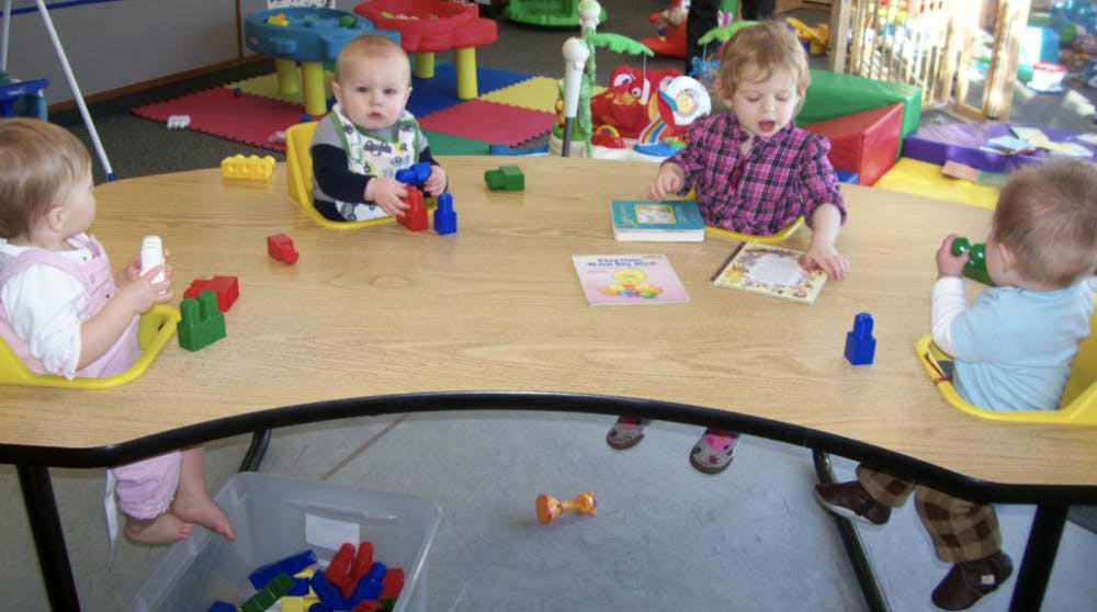 Four children sitting at a table playing with toys and looking at toys