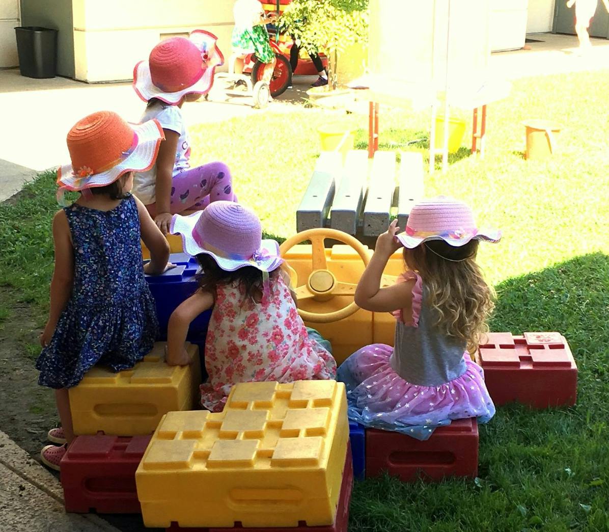 Children playing with toy car and blocks outdoors
