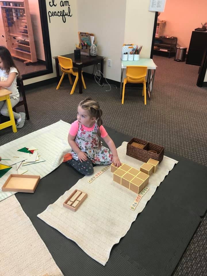 Child playing with wooden blocks on a mat in a classroom