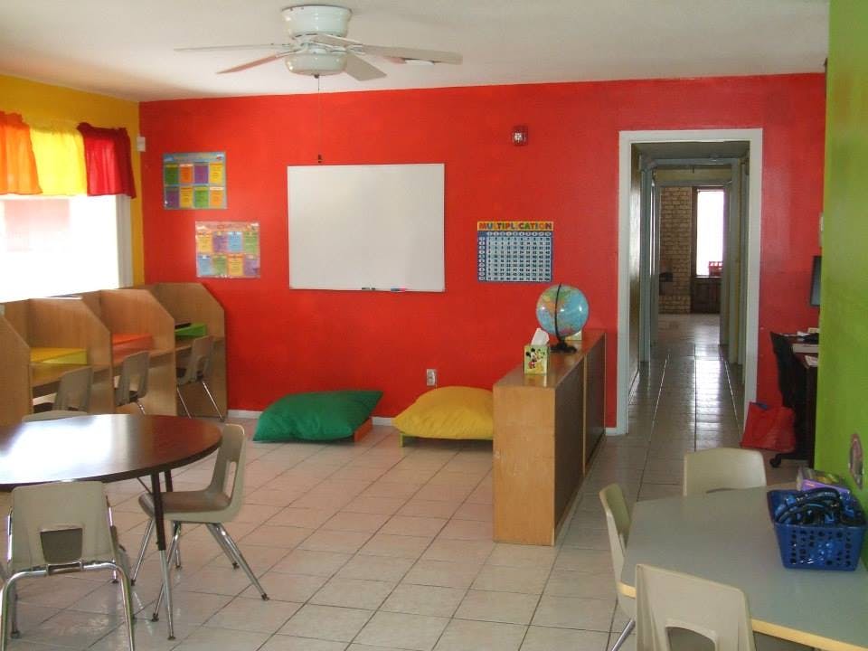 Classroom with red and yellow walls, whiteboard, and tables