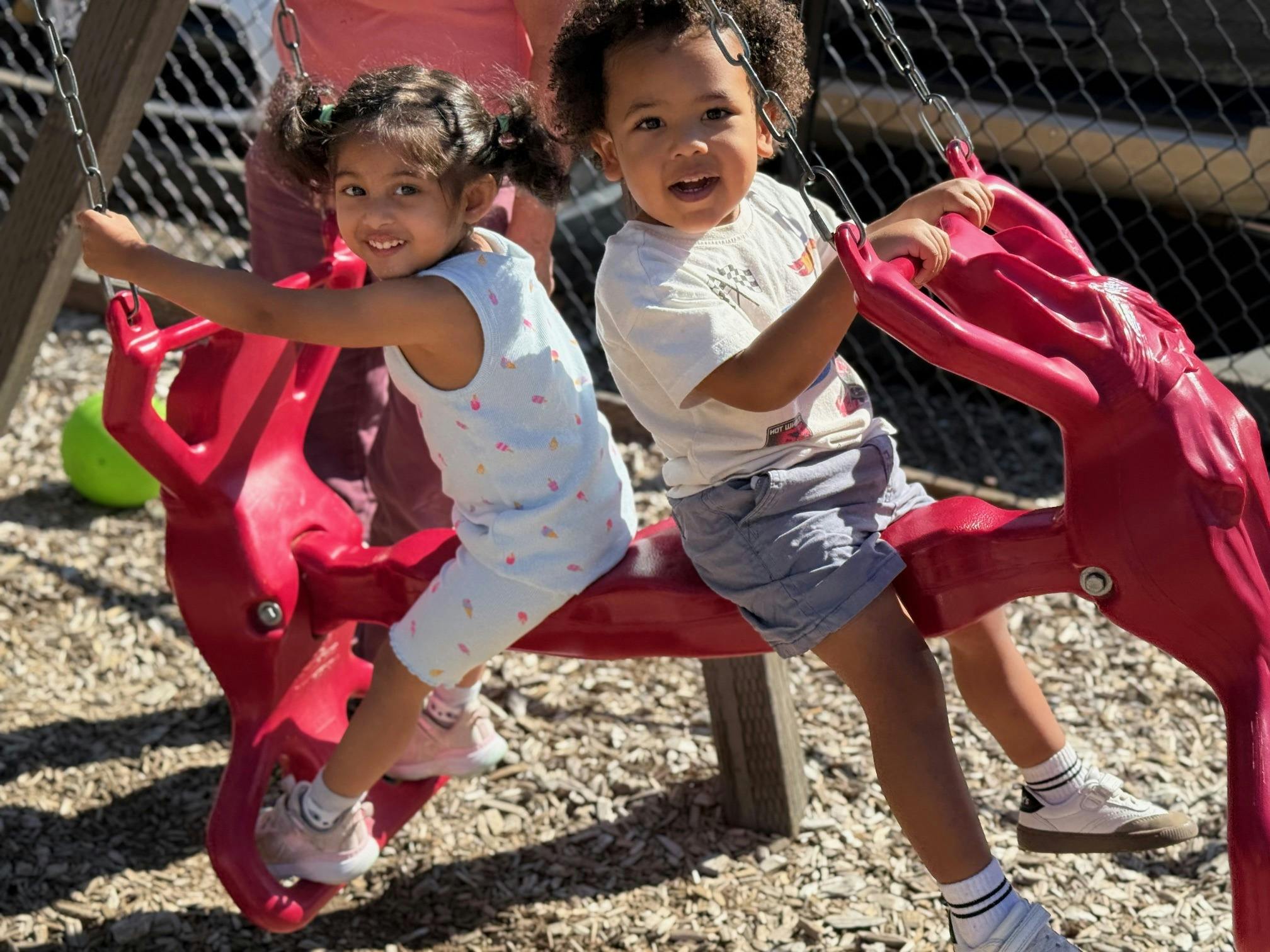 Two children on a red swing set