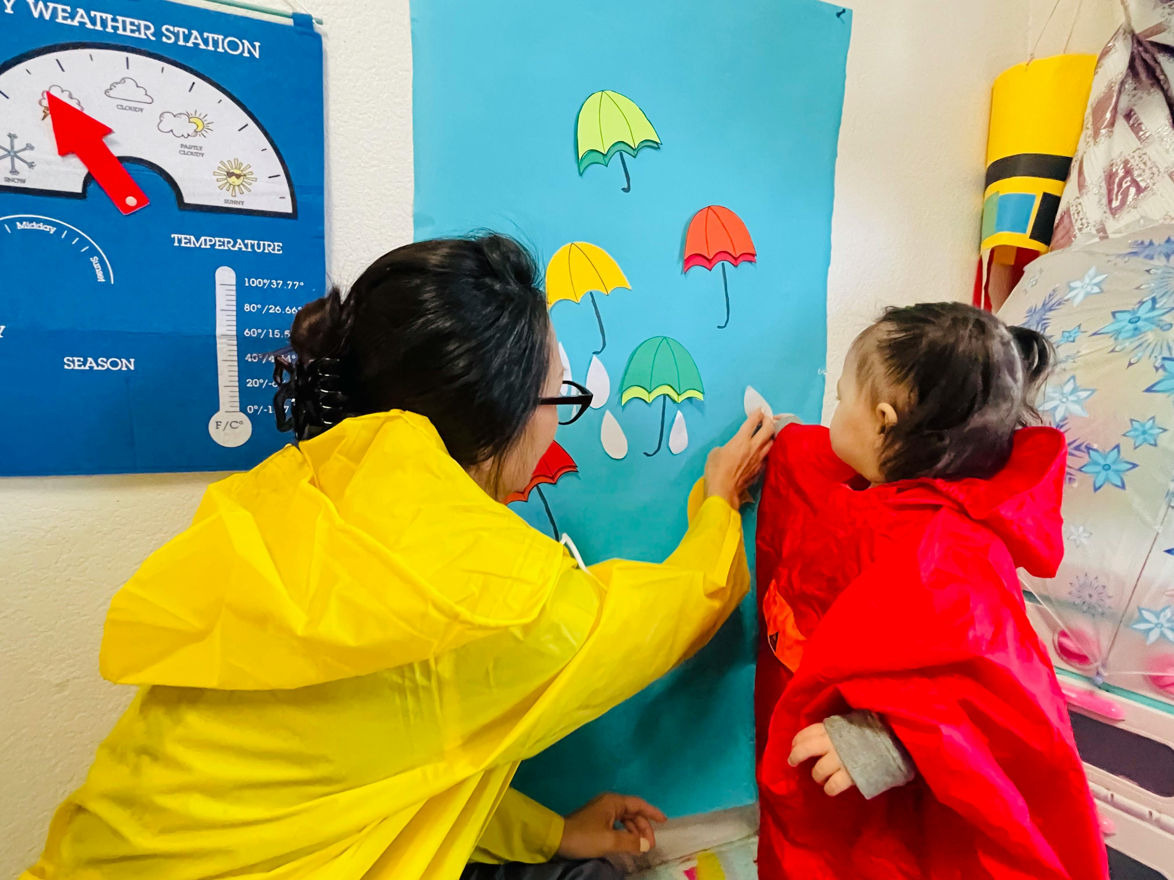 Person and child in raincoats interacting with umbrella cutouts