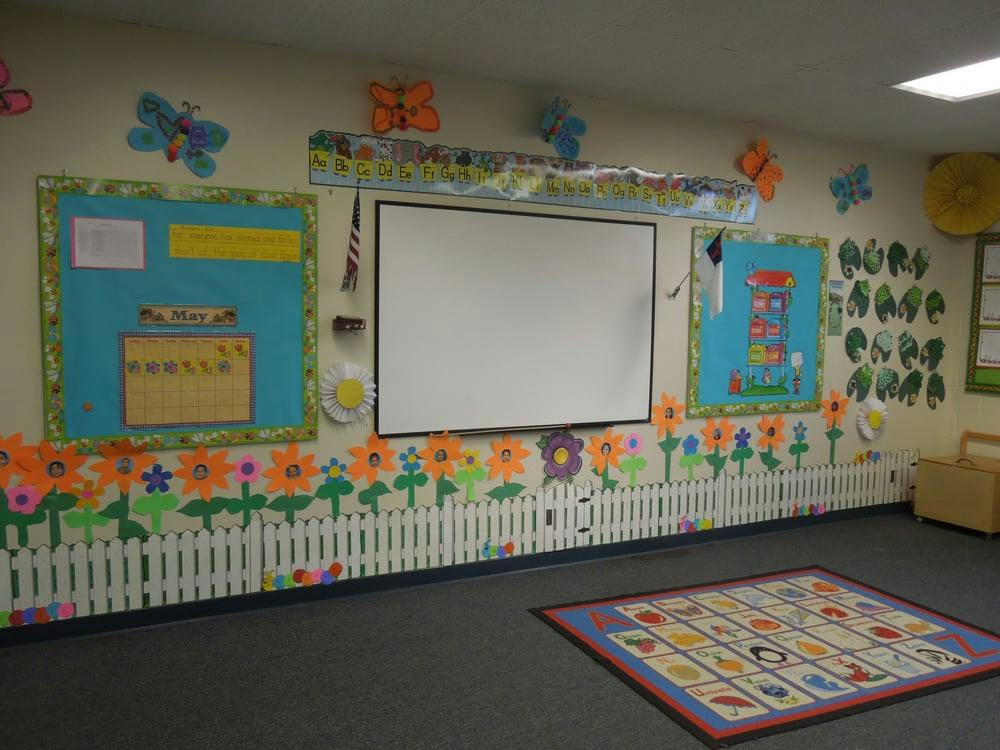 Classroom wall with a whiteboard, bulletin boards, and flower decorations