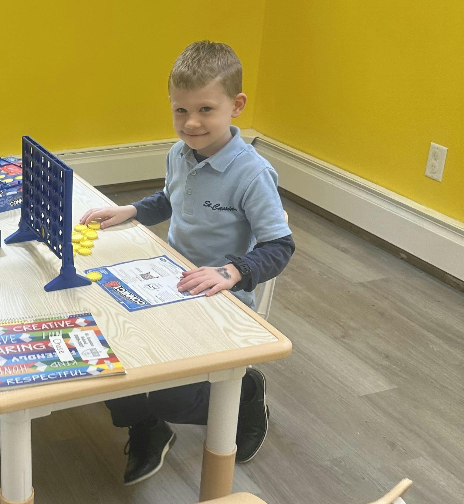 Child playing Connect 4 at a table