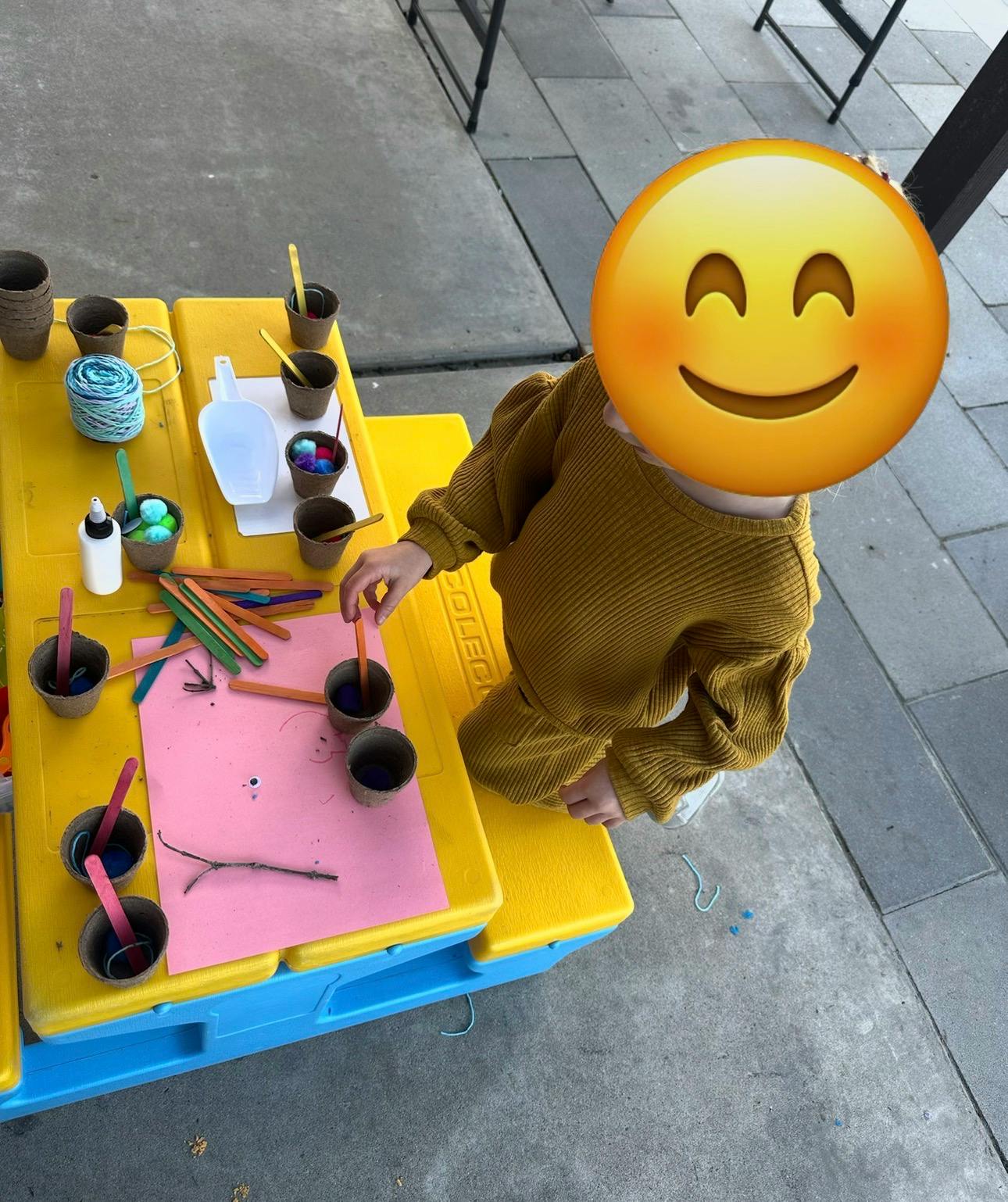 Child at a yellow table playing with craft supplies