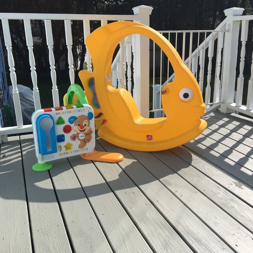Yellow fish-shaped rocking toy and a white activity cube on a deck