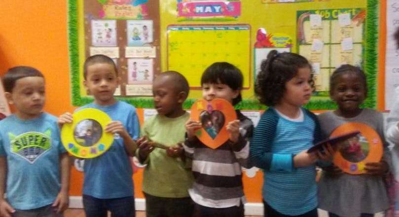 Six children holding up colorful crafts in-class art projects