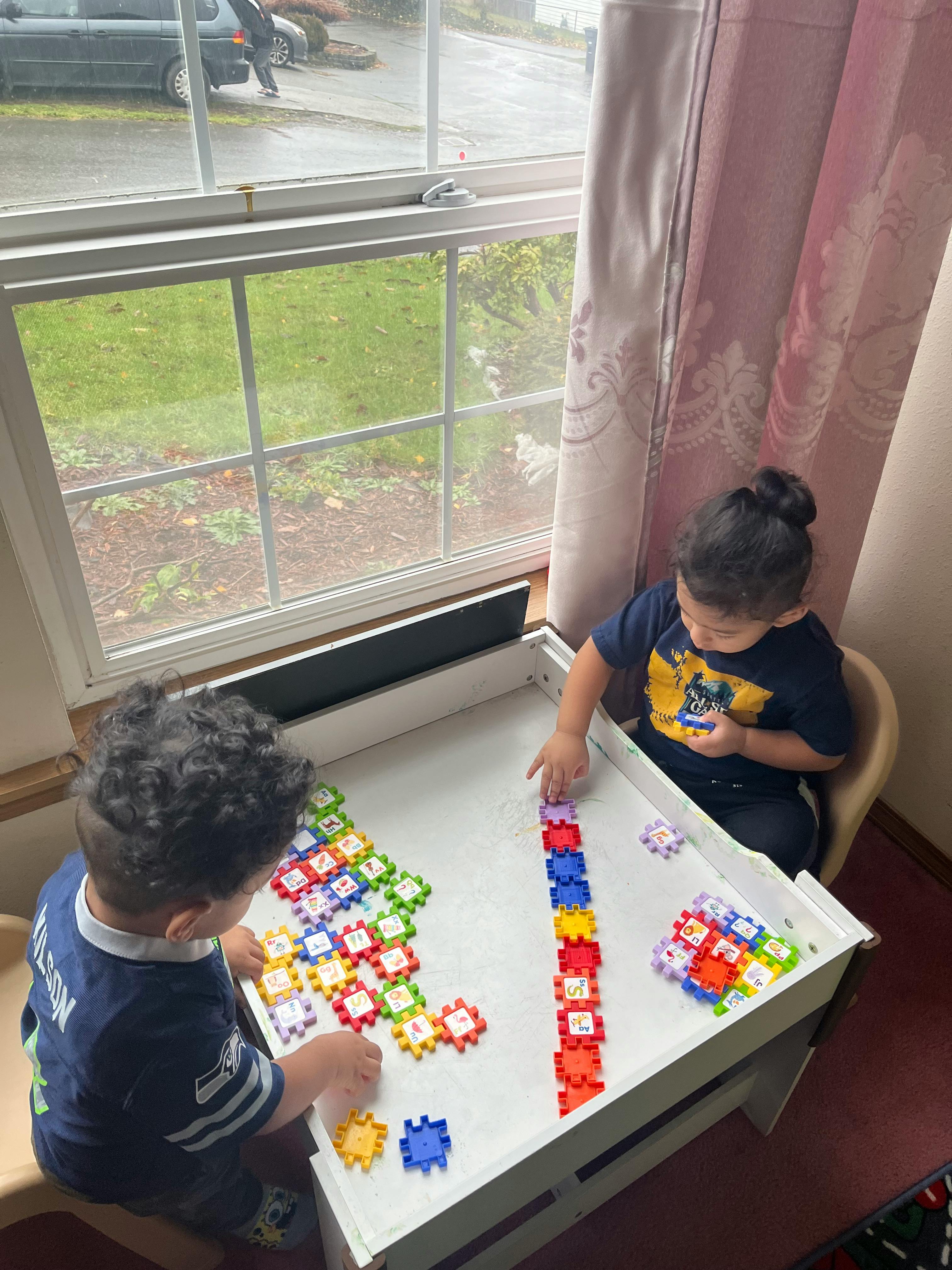 Two children playing with colorful interlocking blocks at a table